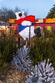 Illuminated polar bear with red scarf and blue vest ice skating at a christmas market in bayonne,