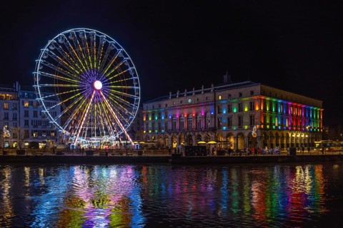 Colorful ferris wheel and city hall reflecting in the river nive in bayonne, france, during
