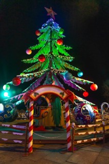 Children enjoying a carousel ride beneath a brightly lit christmas tree at a festive night market