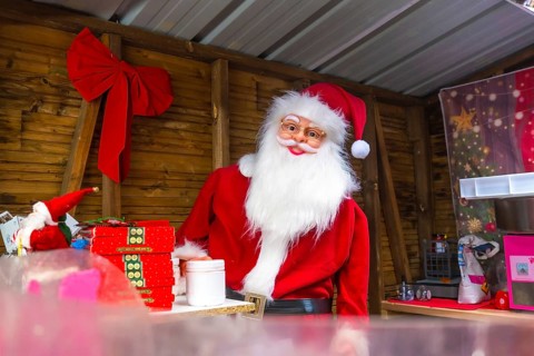 Santa claus impersonator preparing christmas gifts in a wooden kiosk at a christmas market in