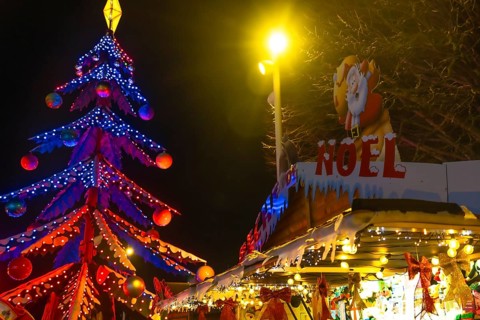 Glowing christmas tree and decorated market stall create festive atmosphere at night in bayonne,