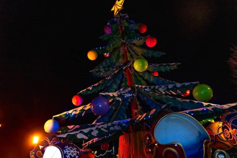Colorful christmas tree with lights and decorations illuminating a carousel at night in bayonne,