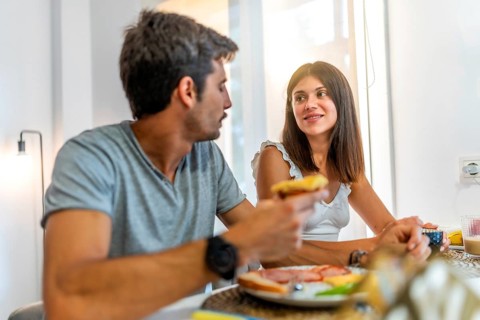Young couple sharing a meal and conversation at their kitchen table, enjoying a relaxing morning