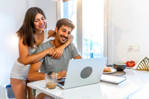 Young couple embracing and enjoying each other's company while working on a laptop in a cozy