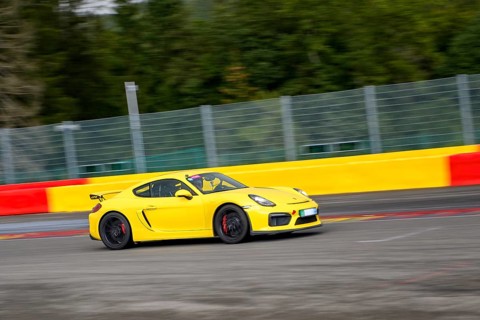 Yellow racing car sports car Porsche Cayman GT4 races at high speed top speed during trackday on