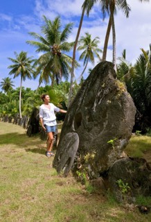 Tourist standing next to oversized huge stone coins real currency in stone money bank stone money