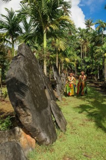 Native couple from Yap in traditional traditional costume walking on path through palm forest