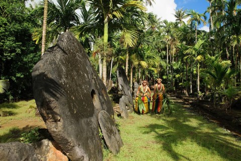 Native couple from Yap in traditional traditional costume walking on path through palm forest