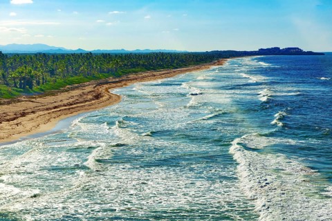 Aerial view of strong surf rolling in with whitecaps at coastal cut-off near Punta Cana, Dominican