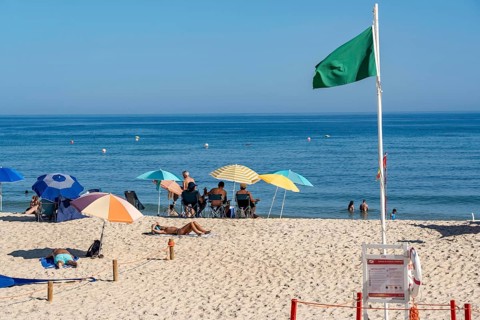 Kilometre-long sandy beach Praia do Barril, on the island off Santa Luzia, green flag indicates