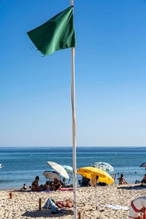 Kilometre-long sandy beach Praia do Barril, on the island off Santa Luzia, green flag indicates