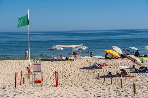 Kilometre-long sandy beach Praia do Barril, on the island off Santa Luzia, green flag indicates