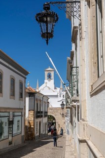 Faro, old town centre alley, R. do Municipio, view of the Arco da Vila city gate, Algarve, Portugal
