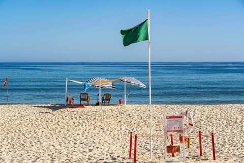 Kilometre-long sandy beach Praia do Barril, on the island off Santa Luzia, green flag indicates