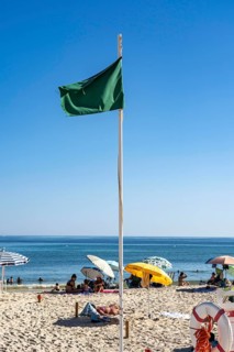 Kilometre-long sandy beach Praia do Barril, on the island off Santa Luzia, green flag indicates