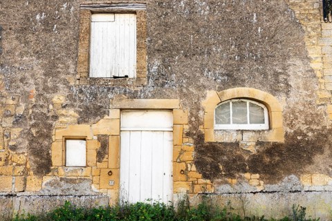 Closed white wooden door and windows, historic house façade, yellow sandstone, Marville,