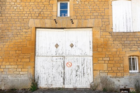 Closed white wooden door and windows, historic house façade, yellow sandstone, Marville,