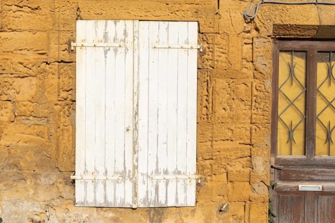 Closed door and white wooden window, historic house façade, yellow sandstone, Marville, Renaissance