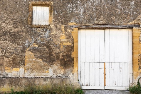 Closed white wooden door and windows, historic house façade, yellow sandstone, Marville,