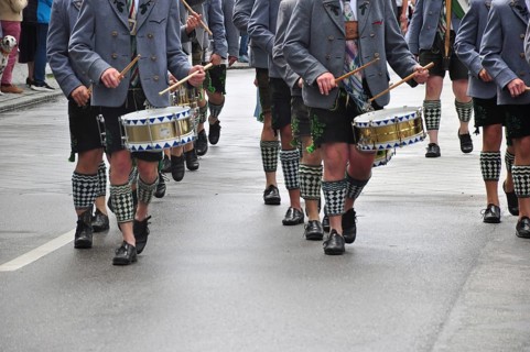 Men in traditional traditional costume play drums during a traditional Bavarian parade,
