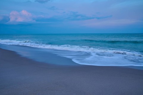 Beach at dusk with gentle waves and blue-grey sky, Cocoa Beach, Port Canaveral, Florida, USA