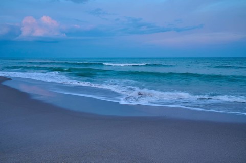 Tranquil beach landscape at dusk with gentle waves and blue sky, Cocoa Beach, Port Canaveral,