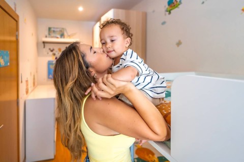 Mom kissing her baby boy in a decorated bedroom, showing love and affection in a cozy home