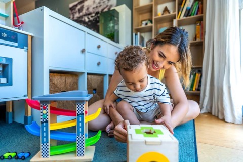 Happy mother and son enjoying playtime together, engaging with colorful educational toys in the