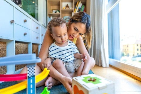 Mom and her son are sitting on the floor enjoying playtime with colorful educational toys,