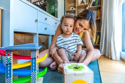 Happy mother and son playing with educational toys, enjoying quality time together in a cozy home