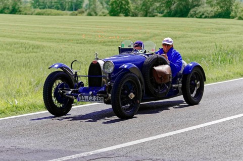 Blue vintage car with male occupants on rural road next to wheat fields, vintage car, car race,