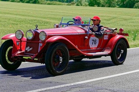 A classic red vintage car with two drivers on a country road, vintage car, car race, Mille Miglia,
