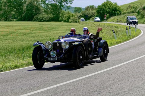 Black classic car with waving driver on winding road in idyllic landscape, classic car, car race,