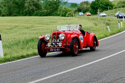 A red classic car with two drivers enjoys a drive in a picturesque landscape, classic car, car