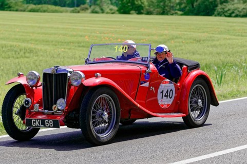 A red classic roadster drives along a rural road in fine weather, classic car, car race, Mille