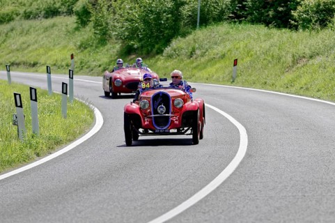 Red classic car in a sharp bend, followed by other classic cars on a country road, classic car, car