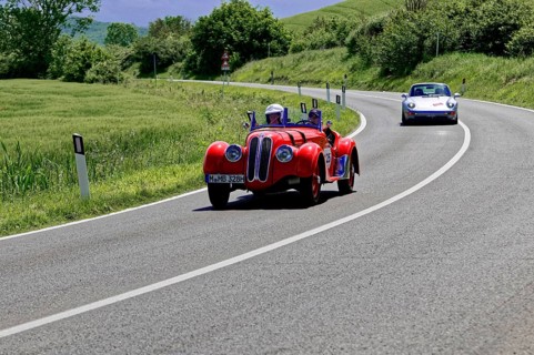 A sporty red vintage car followed by a modern vehicle on a road, vintage car, car race, Mille