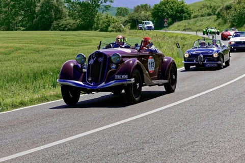Two classic cars driving with several vehicles on a country road, classic car, car race, Mille