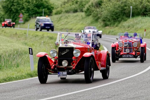 Red classic car in a convoy on a winding country road, classic car, car race, Mille Miglia, 1000
