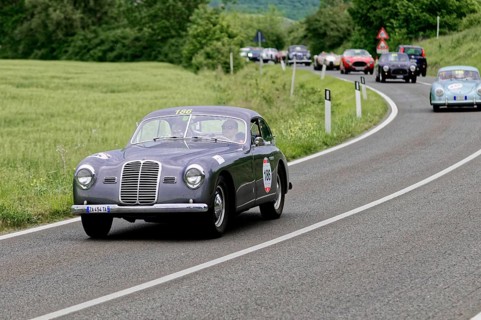 Grey vintage car with race number on a country road, nostalgic atmosphere and historic rally,