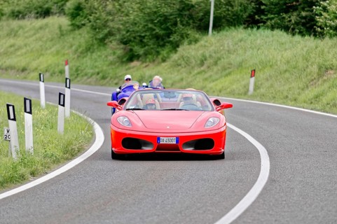 Red Ferrari convertible on winding road surrounded by green landscape, classic car, car race, Mille
