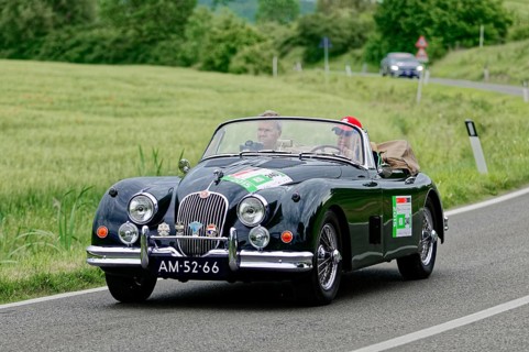 Black convertible driving on a country road through an idyllic landscape, classic car, car race,