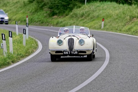 White vintage convertible on a winding country road surrounded by nature, vintage car, car racing,