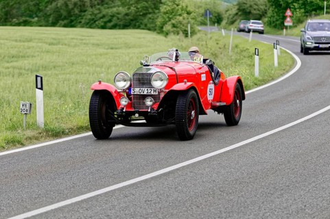 Red vintage car on a country road with green fields and trees, vintage car, car race, Mille Miglia,