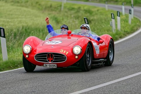 Two people driving in a red Maserati classic car on a winding country road, classic car, car