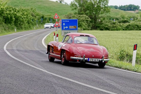 Rear view of a red Mercedes classic car driving on a winding road in a rural setting, classic car,