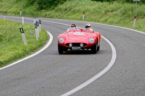 A red vintage convertible car with two occupants drives fast on a tarmac road, vintage car, car