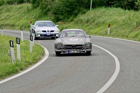 Two classic Mercedes cars driving on a winding country road in a green environment, classic car,