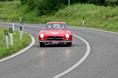 A red Mercedes classic car drives elegantly through a winding country road, classic car, car race,