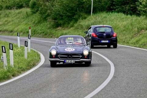 A black Mercedes vintage car drives a small car on a country road, vintage car, car race, Mille